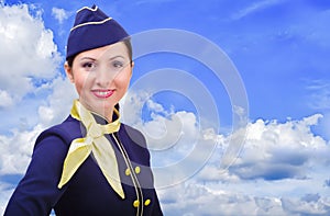 Beautiful smiling stewardess in uniform on a background sky