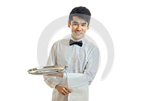 Beautiful smiling waiter with black hair in a white shirt and with a butterfly keeps on hand towel and an empty tray