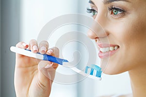 Beautiful Smiling Woman Brushing Healthy White Teeth With Brush.