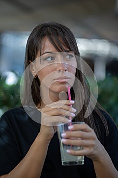 Beautiful smiling woman drinking limunada in garden of cafe