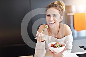 Beautiful Smiling Woman Eating Fresh Organic Vegetarian Salad In Modern Kitchen photo
