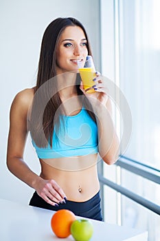 Beautiful smiling woman enjoying a glass of orange juice in the morning