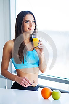 Beautiful smiling woman enjoying a glass of orange juice in the morning