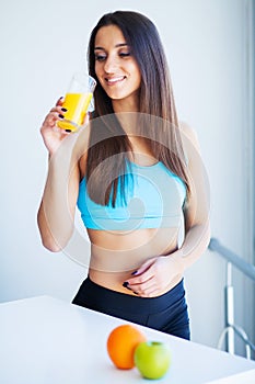 Beautiful smiling woman enjoying a glass of orange juice in the morning