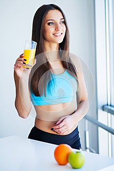 Beautiful smiling woman enjoying a glass of orange juice in the morning