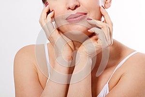 Beautiful smiling woman face close up isolated. Anti age concept. Collagen and plastic surgery. Female touching her face. Red mani