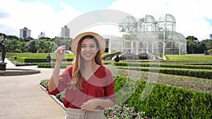 Beautiful smiling woman with hat in the Botanical Garden of Curitiba, Parana, Brazil. Looking at camera. Slow motion