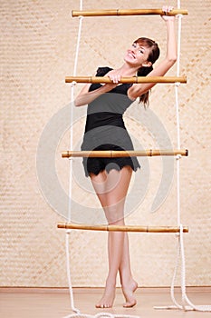 Beautiful smiling woman holds on bamboo rope ladder