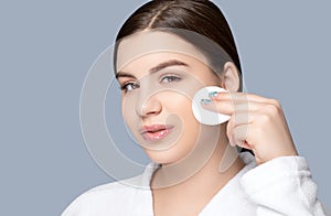 A beautiful smiling woman holds a cotton pad and wipes makeup skin with micellar water. Cosmetology treatment in the beauty salon photo