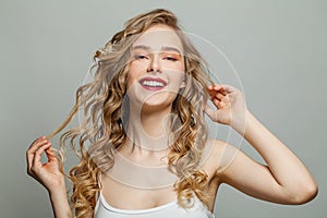 Beautiful smiling woman with long blonde curly hair on white background