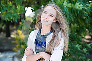 Beautiful smiling woman with long hair standing in the park