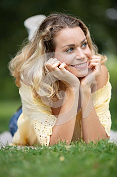 Beautiful smiling woman lying on grass outdoor