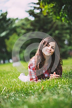 Beautiful smiling woman lying on a grass outdoor.