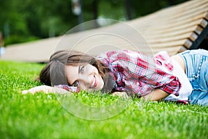 Beautiful smiling woman lying on green grass