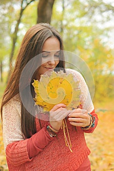 Beautiful smiling woman outdoor portrait, fresh skin and healthy smile, hold maple leaves bouqet front of face