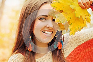 Beautiful smiling woman outdoor portrait, fresh skin and healthy smile, hold maple leaves bouqet front of face