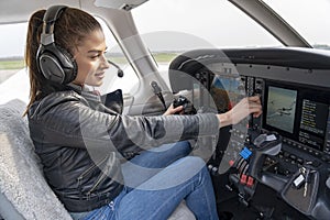 Beautiful Smiling Woman Pilot With Headset Sitting in Cabin of Modern Aircraft