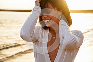 Beautiful smiling woman portrait in sunset on the beach. Girl wearing fashionable gold jewelry