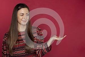 Beautiful smiling woman poses on red background, copy space, she