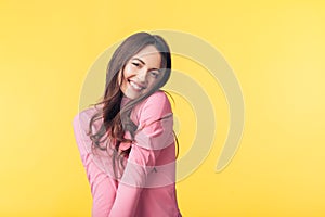 Beautiful smiling woman posing over yellow background