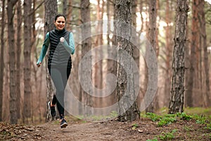 Beautiful Smiling Woman Running on the Forest Trail at Cold Autumn Evening. Sport and Active Lifestyle