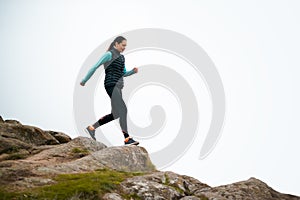 Beautiful Smiling Woman Running on the Mountain Trail at Cold Autumn Evening. Sport and Active Lifestyle