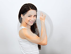 Beautiful smiling woman showing her strong biceps on the arm on blue background. Love yourself body