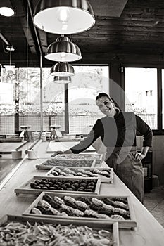 Beautiful smiling woman showing some trays with typical Italian fresh pasta - Young middle eastern sfoglina making fresh pasta in