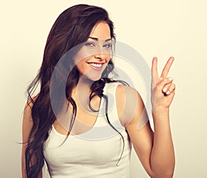 Beautiful smiling woman showing two fingers victory sign in casual clothing. Vintage toned portrait