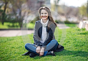 Beautiful smiling woman sitting on a grass outdoor