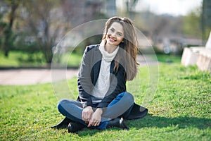Beautiful smiling woman sitting on a grass outdoor