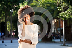 Beautiful smiling woman standing in park talking on mobile phone