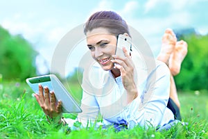 Beautiful smiling woman with tablet pc and talking on mobile phone