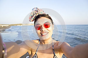 Beautiful smiling woman is taking selfie on the beach.