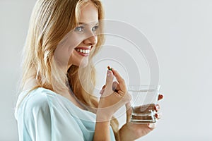 Beautiful Smiling Woman Taking Vitamin Pill. Dietary Supplement