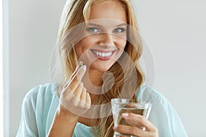 Beautiful Smiling Woman Taking Vitamin Pill. Dietary Supplement