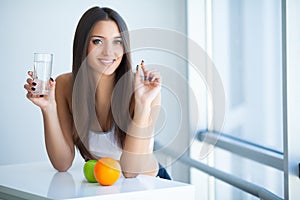 Beautiful Smiling Woman Taking Vitamin Pill and Dietary Supplement photo