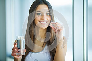 Beautiful Smiling Woman Taking Vitamin Pill. Dietary Supplement photo