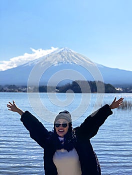 Beautiful smiling woman tourists are traveling and feel happy with Mt Fuji in the morning on the lake kawaguchiko, Japan