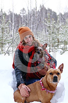 Beautiful smiling woman is on a walk with her two dogs in winter coniferous forest