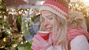 Beautiful smiling woman in warm clothing with red cup of hot tea or coffee