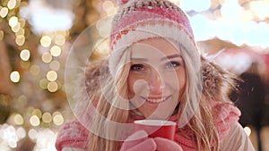 Beautiful smiling woman in warm clothing with red cup of hot tea or coffee