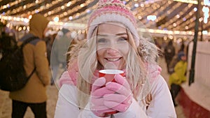 Beautiful smiling woman in warm clothing with red cup of hot tea or coffee