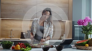Beautiful Smiling Woman Watches Online Recipe from a Tablet and Repeats the Process.