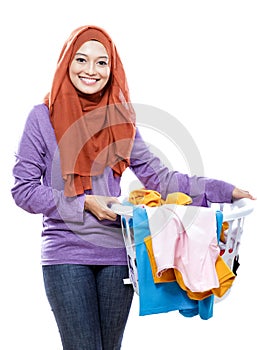 Beautiful smiling woman wearing hijab holding a laundry basket