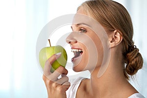 Beautiful Smiling Woman With White Teeth Eating Green Apple