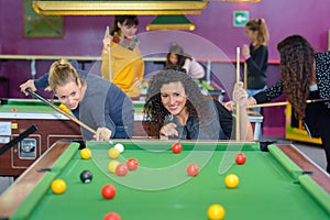 Beautiful smiling women playing billiards at bar