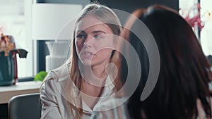 Beautiful smiling young 20-25 year old Caucasian blonde woman taking job interview at modern loft office meeting table.