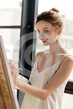 beautiful smiling young artist painting picture