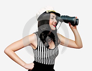 Beautiful smiling young brunette woman sailor looking away through binoculars on white